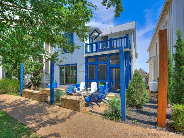 back of property featuring a balcony, a patio area, and metal roof