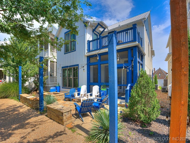 back of property featuring a balcony, metal roof, and a patio