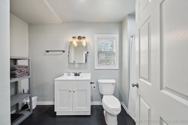 bathroom featuring toilet, vanity, and baseboards