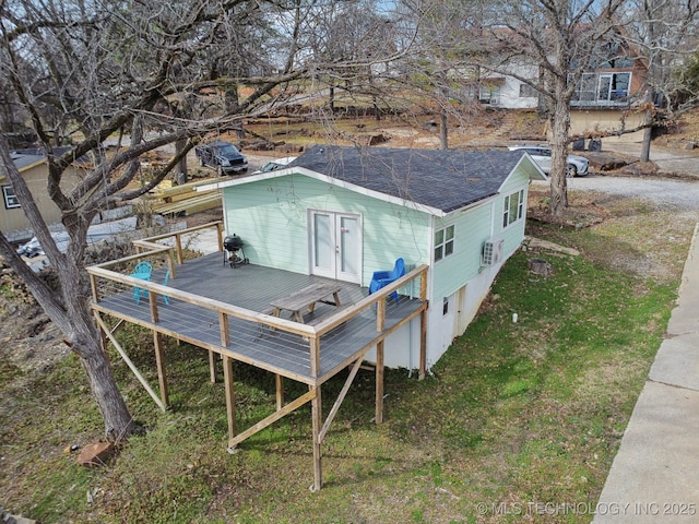 rear view of property featuring french doors, a deck, and roof with shingles