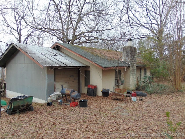 view of front facade featuring concrete block siding, a chimney, and a shingled roof