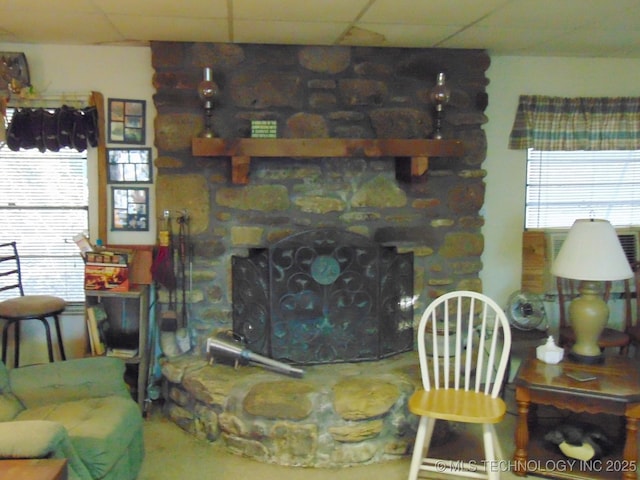 living room with a paneled ceiling and a stone fireplace