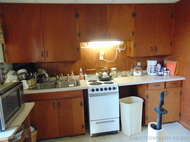 kitchen featuring electric range, stainless steel microwave, light countertops, and a sink