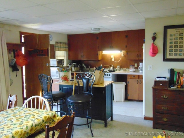 kitchen featuring stainless steel microwave, a paneled ceiling, and light countertops