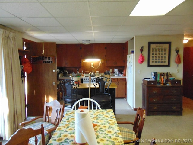 dining area with a paneled ceiling and light carpet