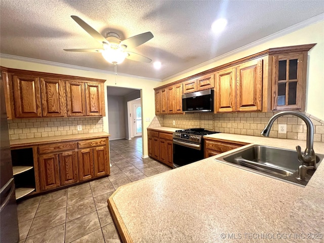 kitchen featuring brown cabinets, ornamental molding, a sink, appliances with stainless steel finishes, and light countertops