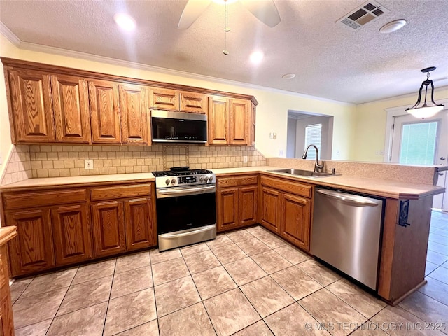 kitchen with brown cabinetry, visible vents, a sink, light countertops, and appliances with stainless steel finishes