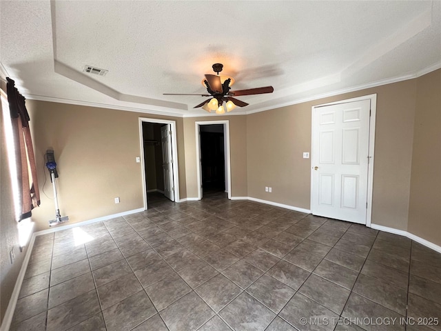 unfurnished bedroom featuring visible vents, a walk in closet, ornamental molding, a textured ceiling, and baseboards