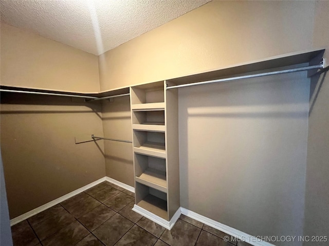 walk in closet with dark tile patterned flooring