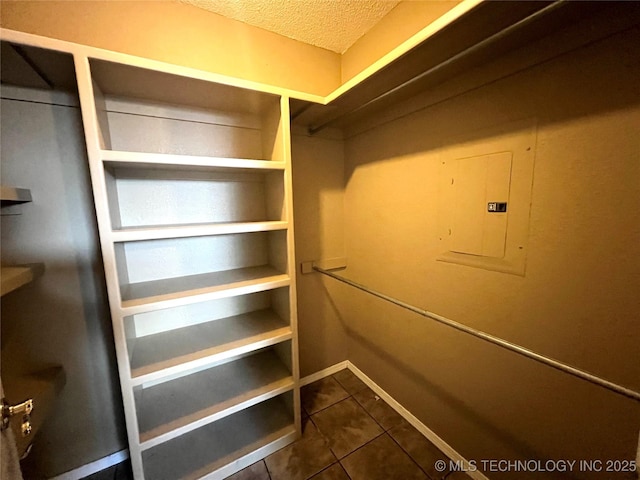 spacious closet with electric panel and dark tile patterned flooring