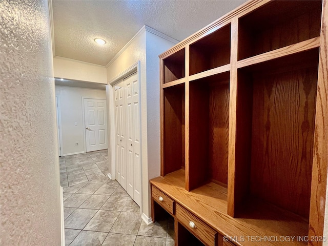 mudroom featuring light tile patterned floors, a textured ceiling, and a textured wall