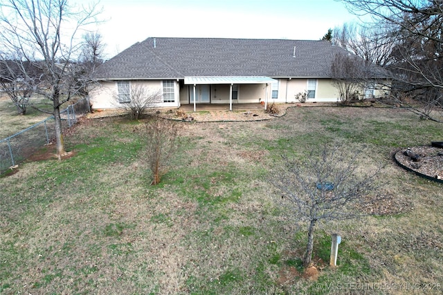 rear view of property featuring fence, roof with shingles, stucco siding, a lawn, and a patio