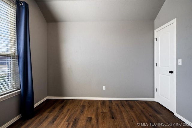 empty room featuring baseboards and dark wood-type flooring