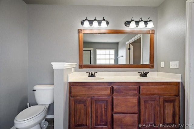 bathroom featuring double vanity, toilet, and a sink