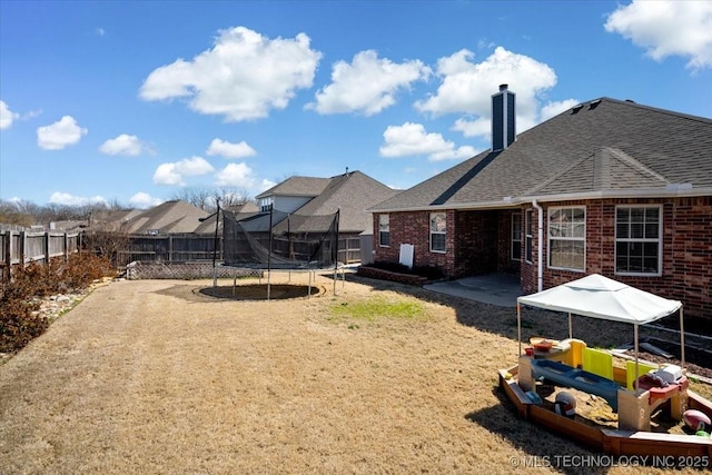 view of yard with a fenced backyard, a patio, and a trampoline