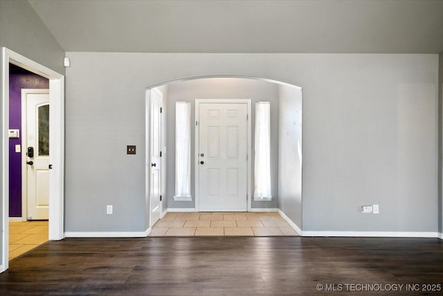 entryway featuring arched walkways, baseboards, and wood finished floors