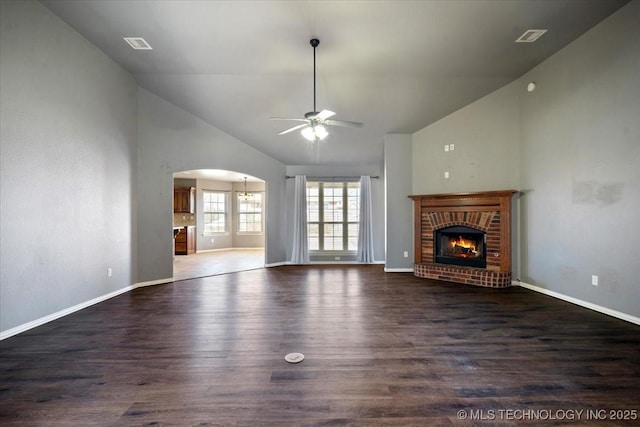 unfurnished living room featuring visible vents, a fireplace, wood finished floors, arched walkways, and a ceiling fan