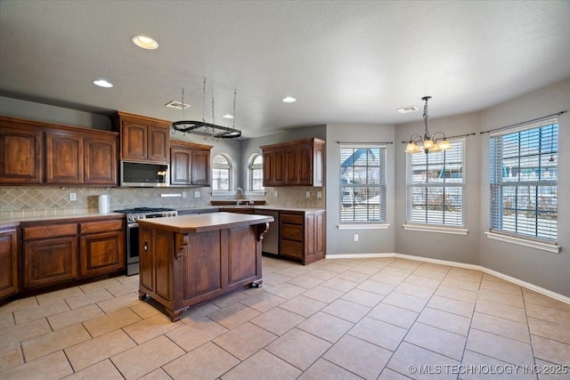 kitchen featuring backsplash, a center island, light countertops, light tile patterned floors, and stainless steel appliances