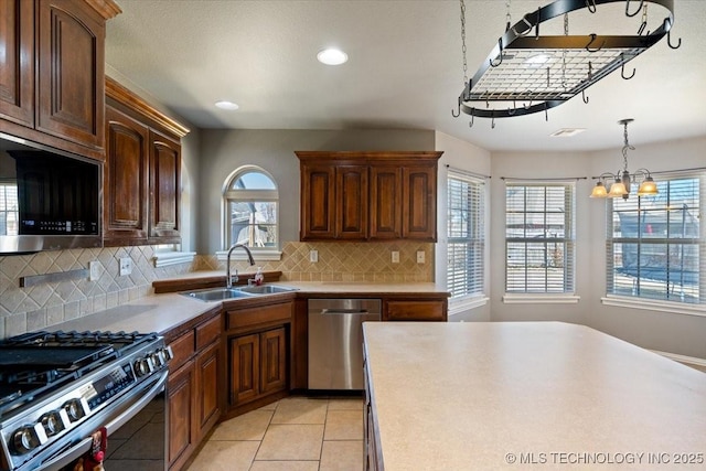 kitchen with a sink, appliances with stainless steel finishes, light tile patterned flooring, and light countertops