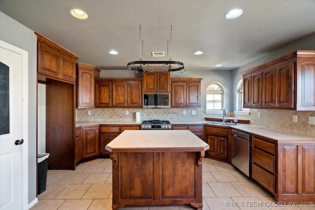 kitchen with a center island, light countertops, appliances with stainless steel finishes, light tile patterned flooring, and a sink