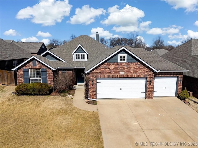 view of front of home with driveway, roof with shingles, a front yard, a garage, and brick siding