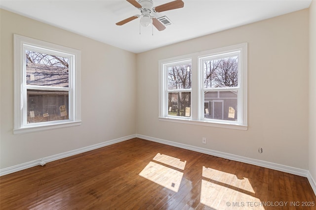 spare room featuring hardwood / wood-style floors, plenty of natural light, and baseboards