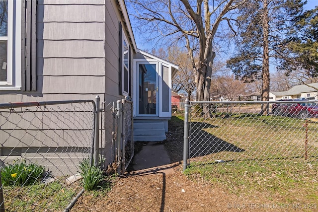 view of side of property featuring fence, a lawn, and a gate