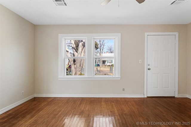 empty room featuring hardwood / wood-style flooring, baseboards, visible vents, and ceiling fan