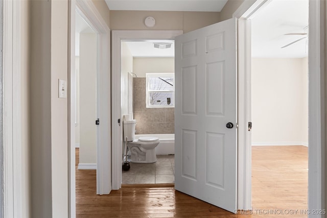 corridor with visible vents, baseboards, and wood finished floors