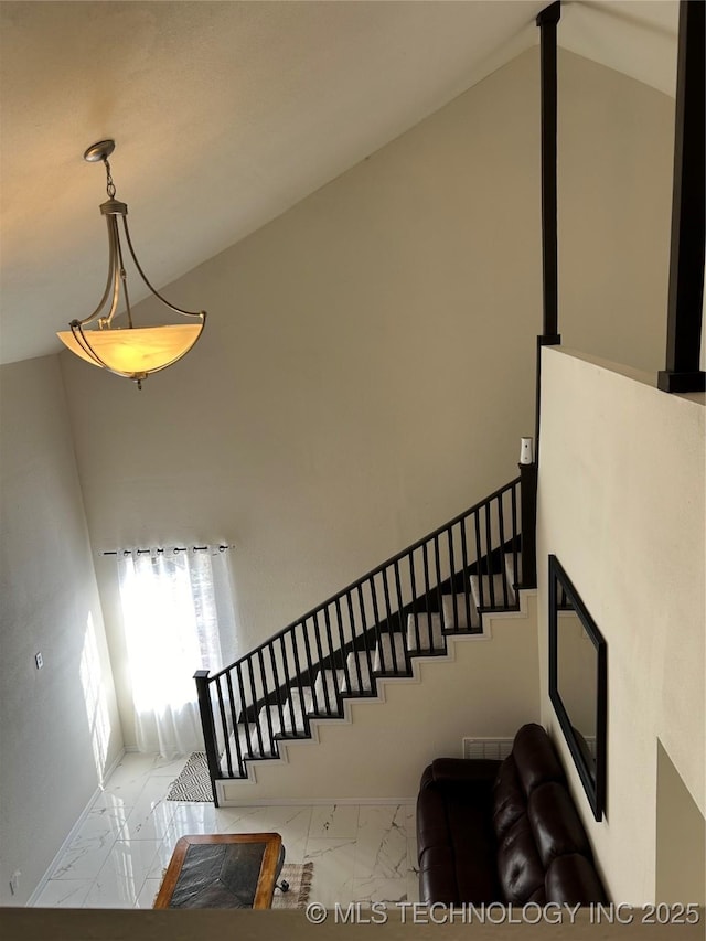 stairs featuring marble finish floor and high vaulted ceiling