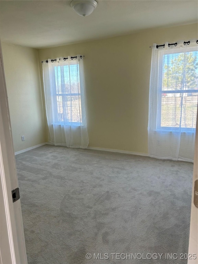 carpeted spare room with a healthy amount of sunlight and baseboards