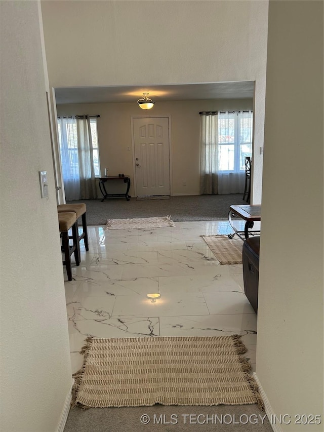 corridor with a healthy amount of sunlight, marble finish floor, and baseboards