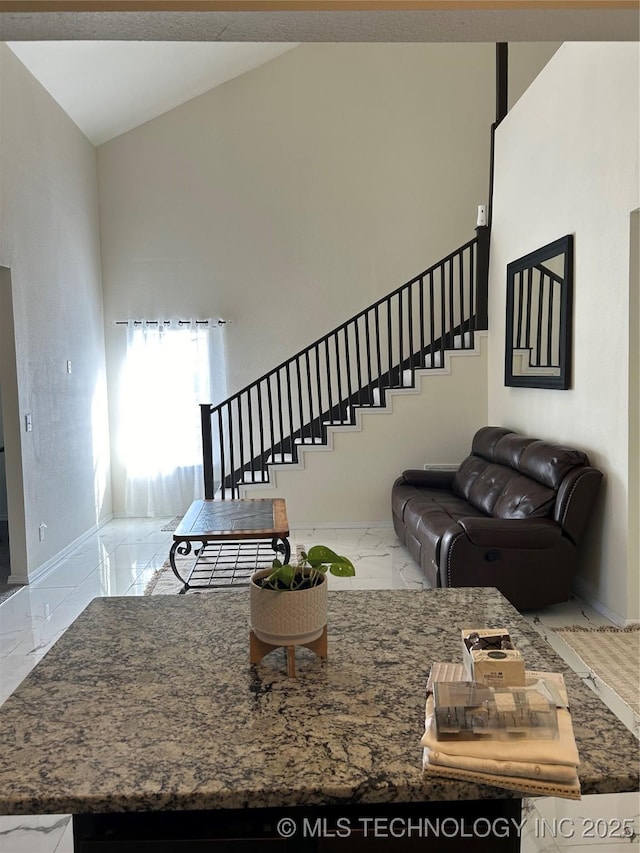 living area featuring marble finish floor, high vaulted ceiling, stairs, and baseboards