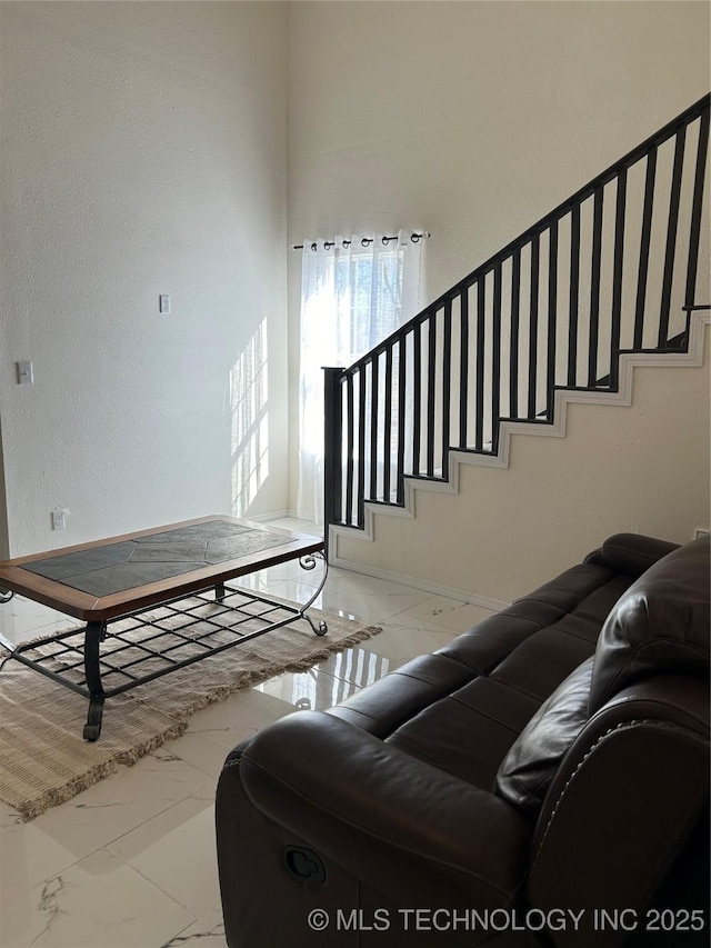 living area featuring stairway and marble finish floor