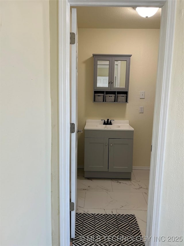 bathroom with vanity, baseboards, and marble finish floor