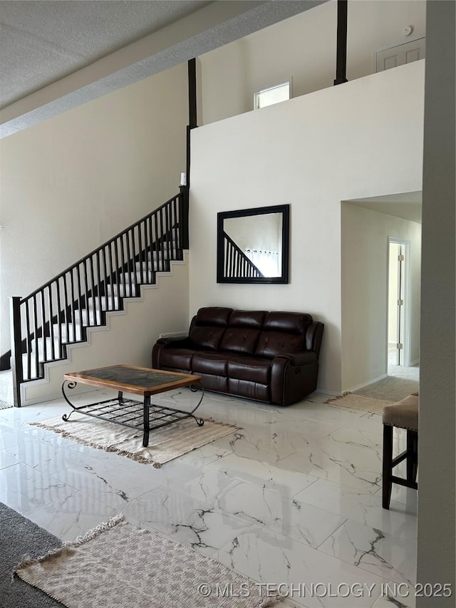 living area with stairs, a high ceiling, and marble finish floor