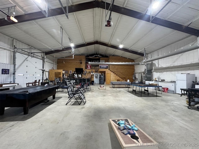 garage with a garage door opener, metal wall, and freestanding refrigerator