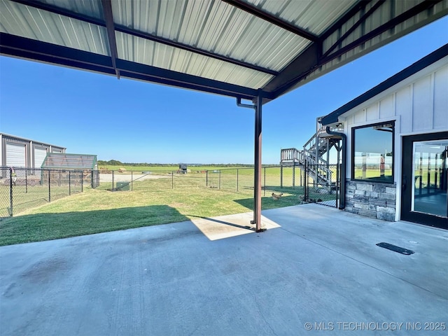 view of patio / terrace featuring a rural view, stairs, and fence