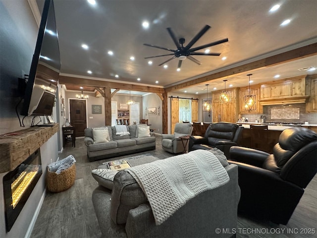 living room featuring a glass covered fireplace, a barn door, wood finished floors, and ornamental molding