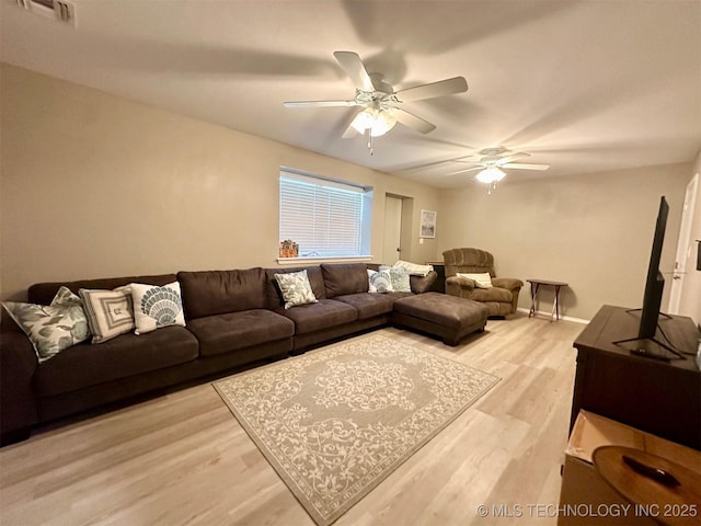 living area featuring visible vents, baseboards, light wood-style floors, and a ceiling fan