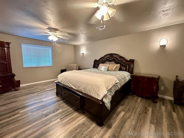 bedroom featuring visible vents, a ceiling fan, baseboards, and wood finished floors