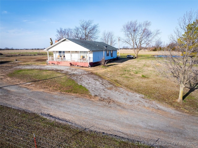 view of front of house with a front lawn, a porch, and dirt driveway