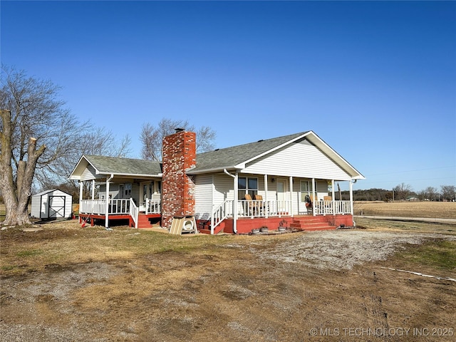 back of house featuring an outbuilding, a shed, covered porch, and a chimney