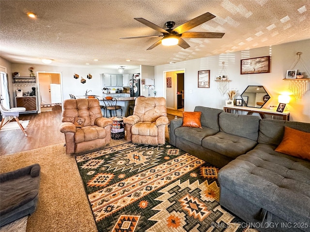 living area featuring a textured ceiling, a ceiling fan, and wood finished floors