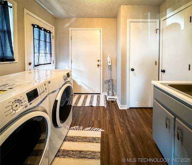 washroom featuring independent washer and dryer, a sink, a textured ceiling, dark wood finished floors, and cabinet space