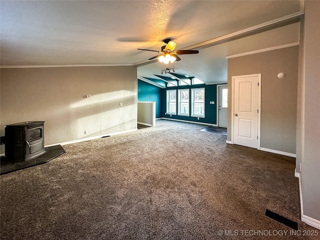 unfurnished living room with baseboards, lofted ceiling, ornamental molding, carpet flooring, and a wood stove