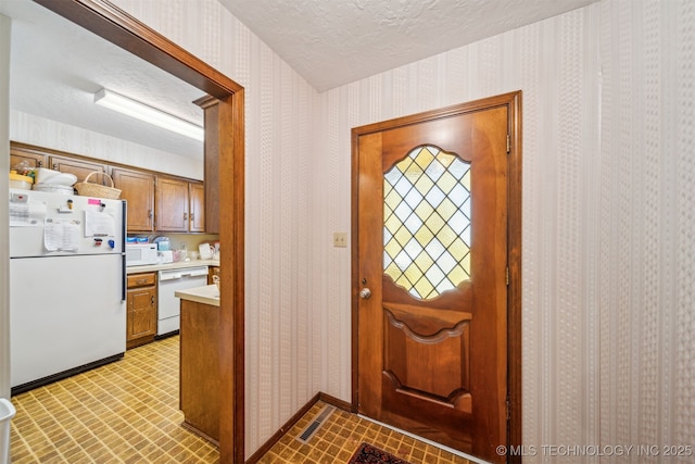 entryway with wallpapered walls, light floors, baseboards, and a textured ceiling