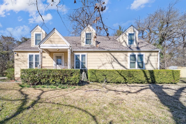 new england style home with a shingled roof and a front lawn