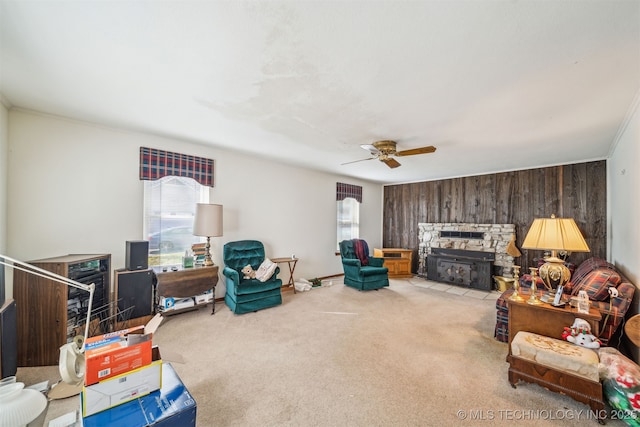 living area featuring a stone fireplace, plenty of natural light, carpet, and wood walls