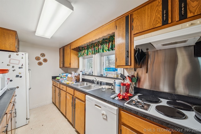 kitchen with white appliances, brown cabinetry, and a sink